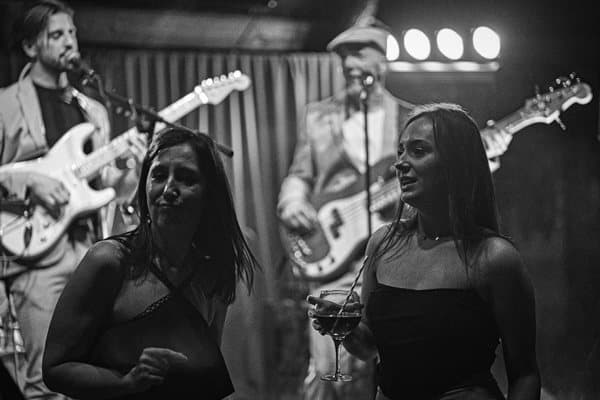 Black and white shot of guests dancing in front of the band at Akamba